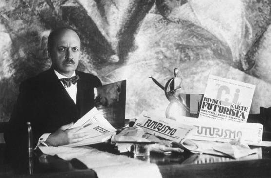 Filippo Tommaso Marinetti seated at a desk surrounded by Futurist publications and artwork